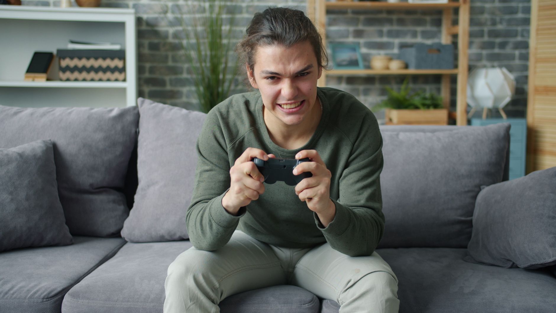 Young adult intensely playing video games on a couch in a cozy living room setting. — How a Slot Website Delivers a Smooth an
