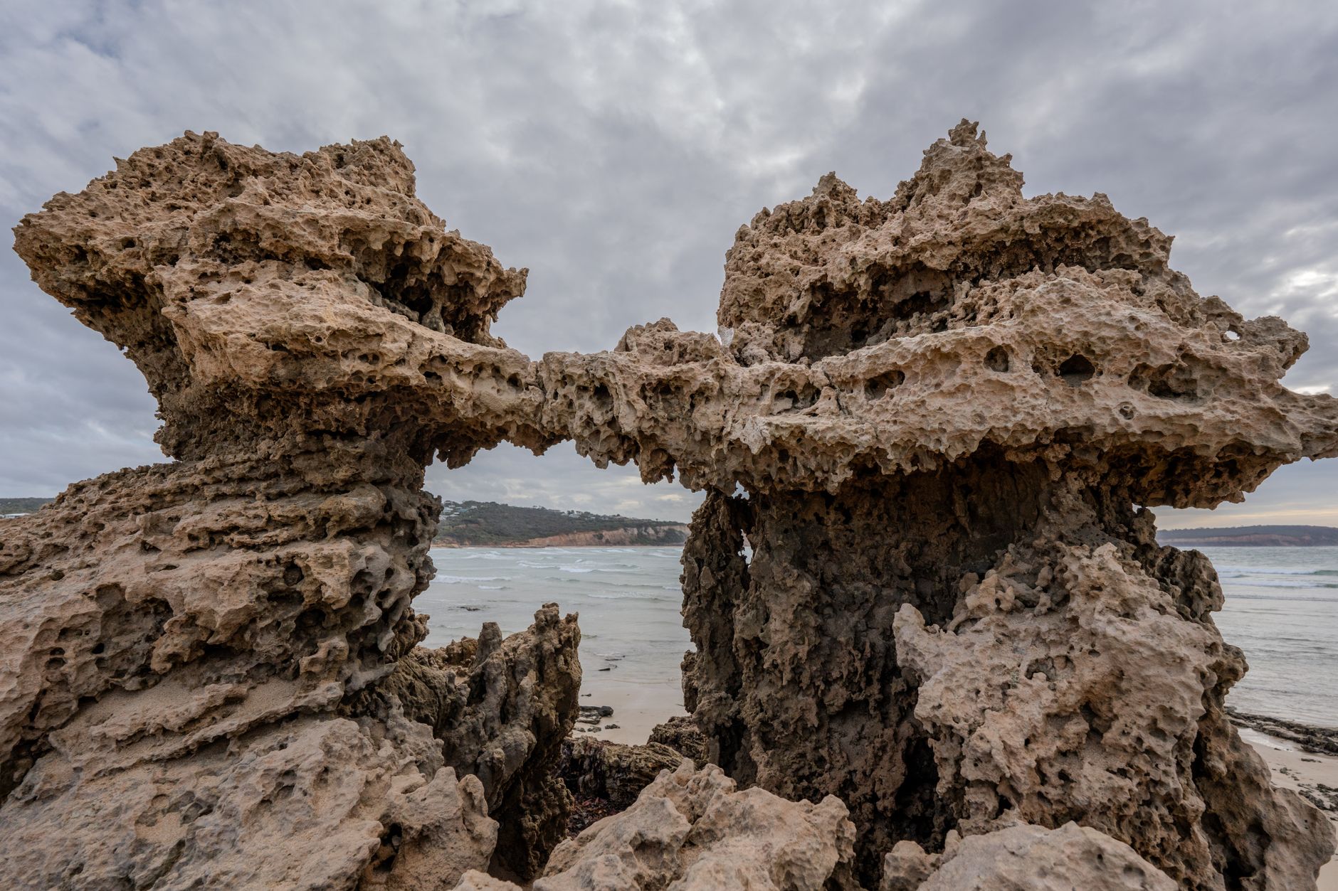 A striking coastal rock formation displaying natural erosion against a cloudy backdrop by the sea. — Online Casino Direct Web